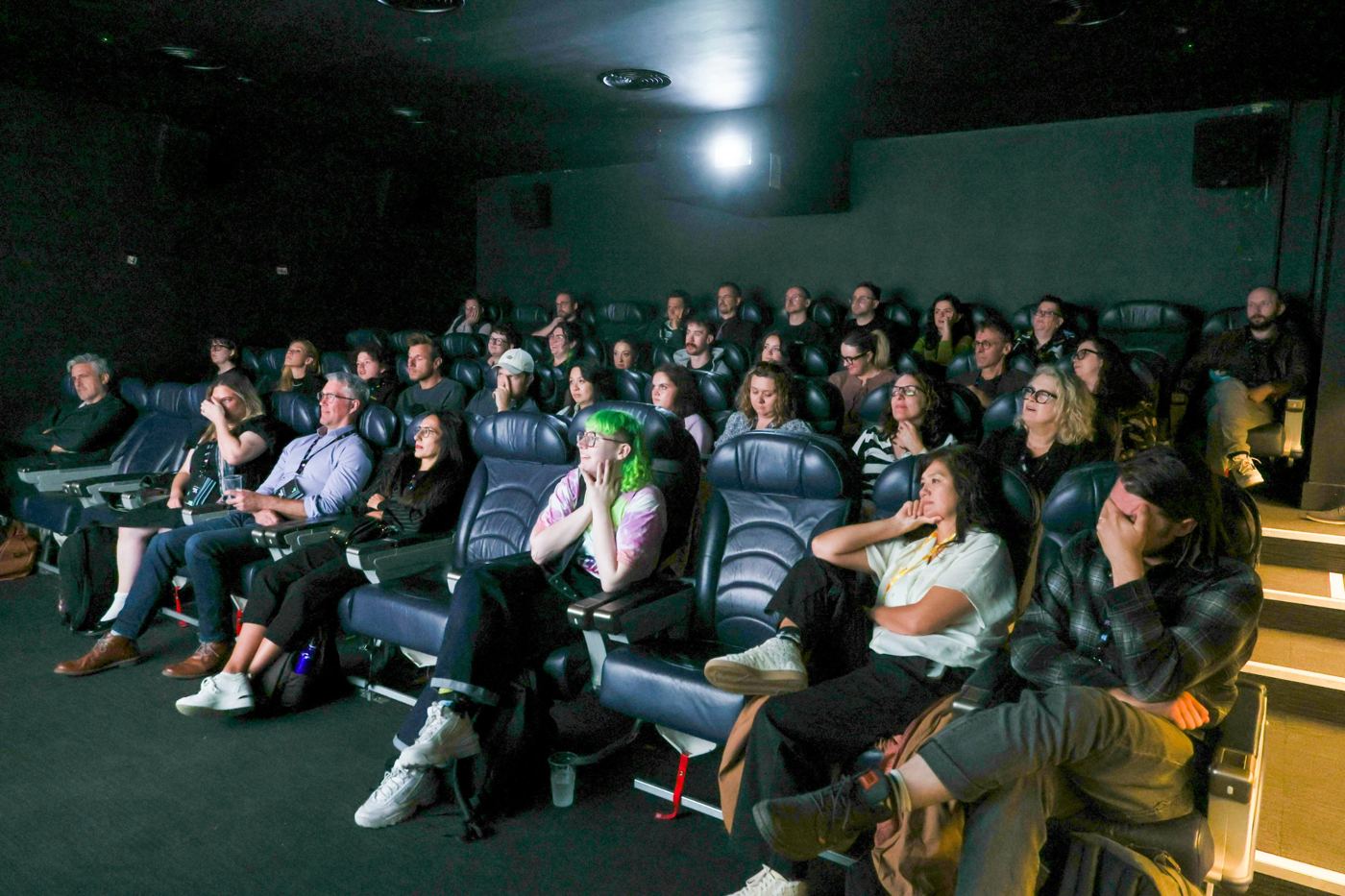 Audience watching a screening in a cinema fitted with aircraft-style seats