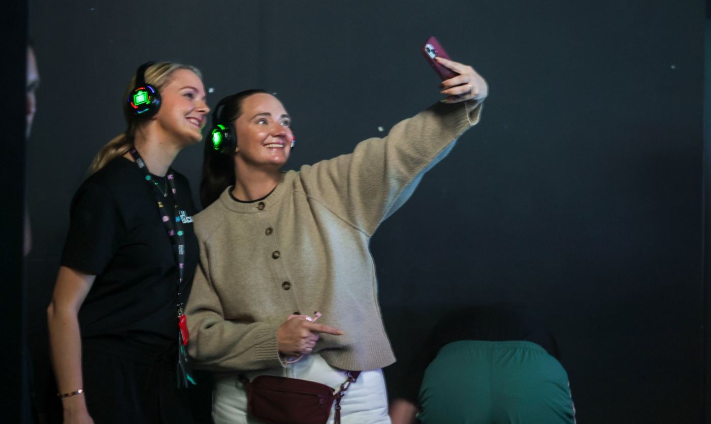 Two attendees in light-up headsets taking a selfie