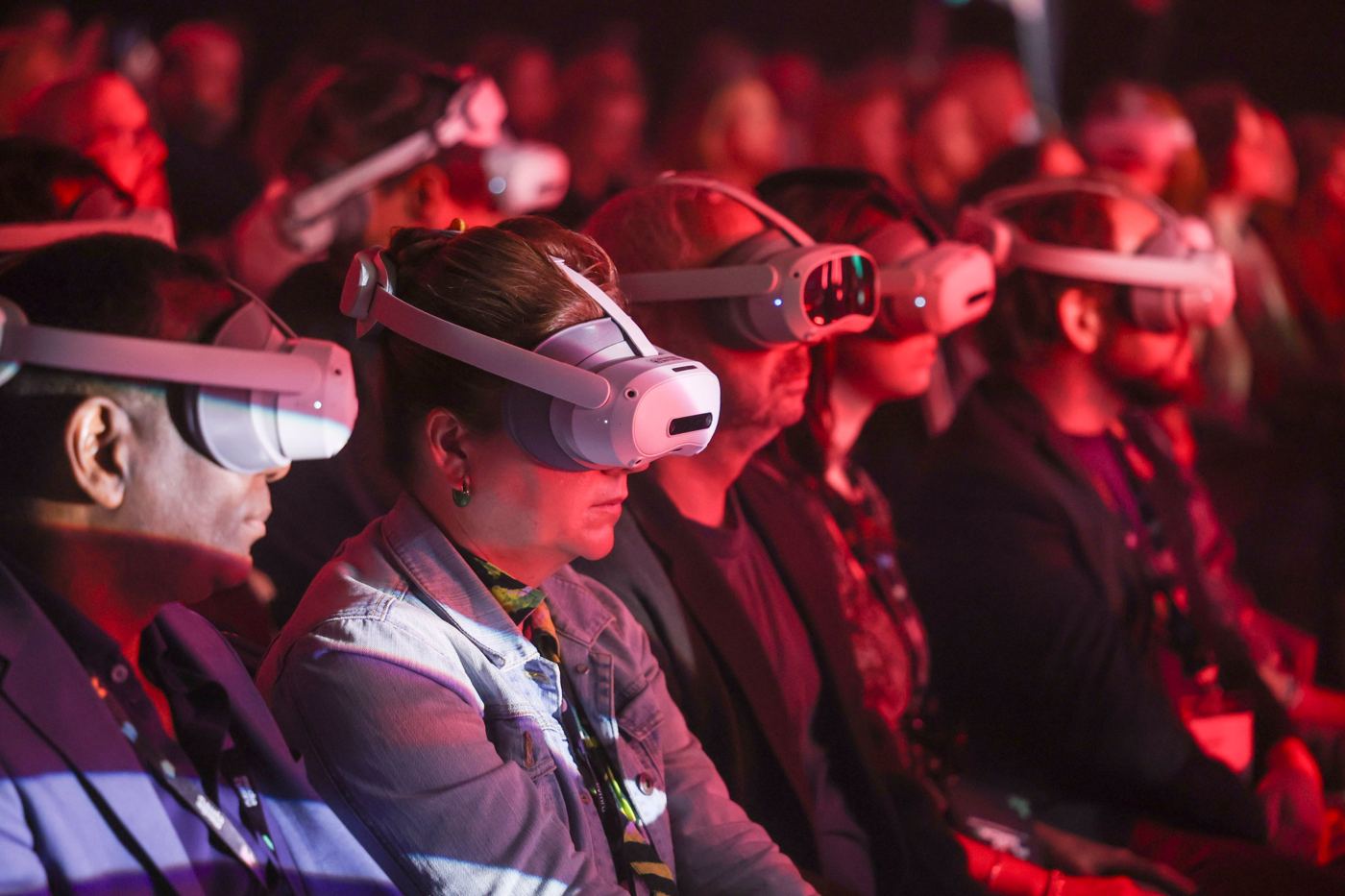 Audience wearing VR headsets under red stage light at an immersive event
